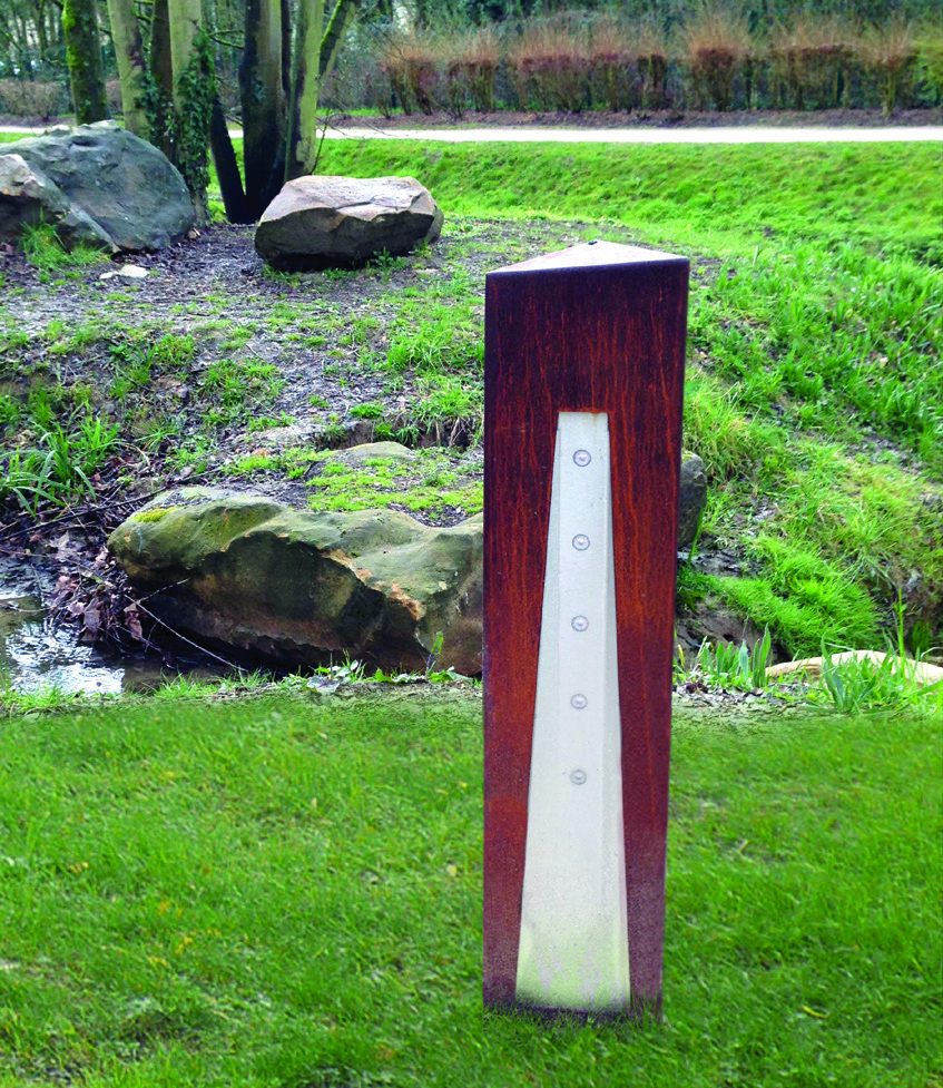 Borne lumineuse Logiq à l'aspect corten, dans un jardin