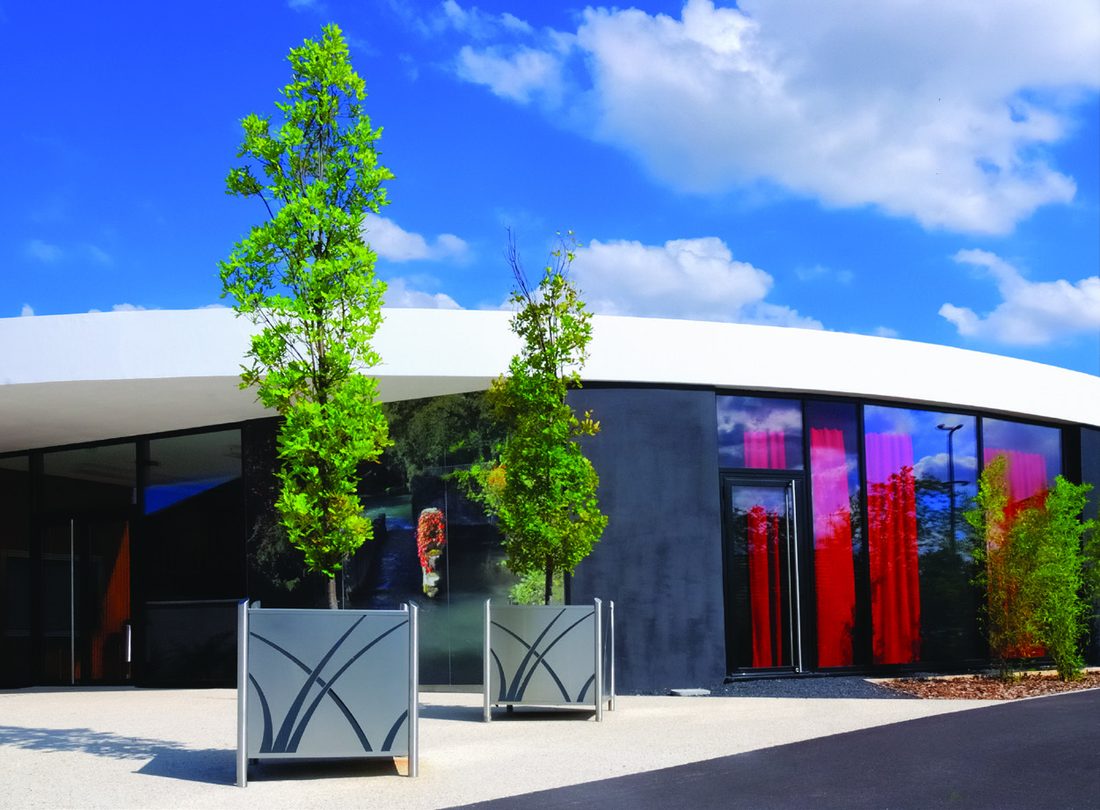 Jardinières Camino plantées d'arbres devant un bâtiment contemporain